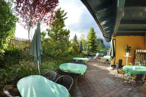 a patio with tables and chairs and an umbrella at Apparthotel Bliem in Schladming