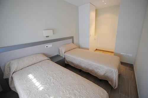a small room with two beds in it at Apartamentos Turísticos Mirablanc in Valjunquera