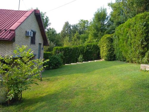 un patio con una casa y un césped con un seto en Holiday Home Zbilje, en Visoko