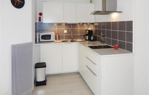a kitchen with white cabinets and a microwave at Nice Apartment In Gruissan With Kitchen in Gruissan