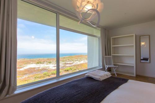 Un dormitorio con un gran ventanal con vista al mar. en Santa Cruz Ocean View Villa, en Bombardeira