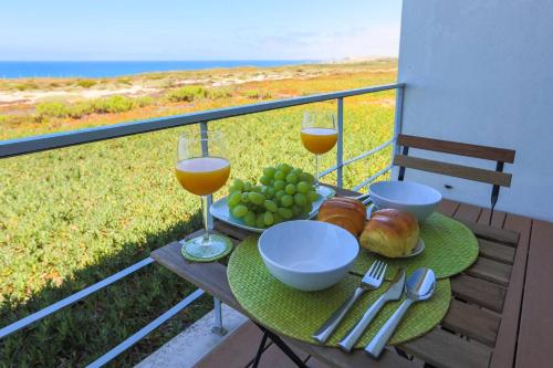 a table with two glasses of wine and food on a balcony at Santa Cruz Ocean View Villa in Bombardeira