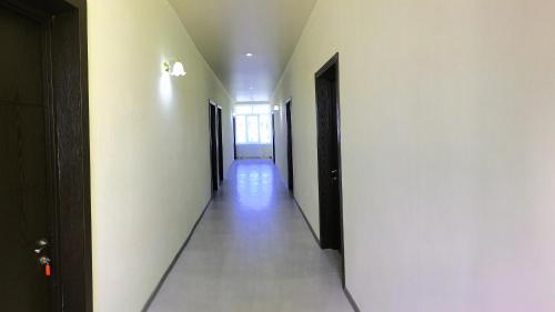 a hallway with white walls and a long hallway with black doors at Golden House in Anaklia