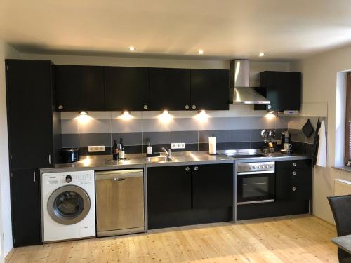 a kitchen with black cabinets and a washing machine at Tritt ein bring Glück herein - Exquisite 75 qm - Messenähe - Parkplatz - Flughafennähe in Düsseldorf
