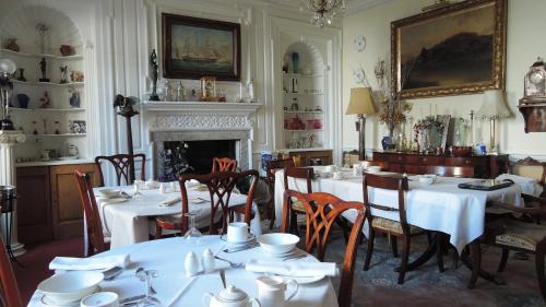 a dining room with white tables and chairs and a fireplace at The Georgian House in Watchet