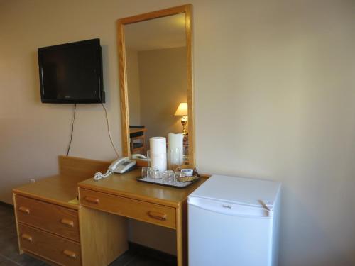 a room with a desk with a refrigerator and a mirror at Cactus Tree Inn in Oliver