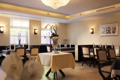 a dining room with a table with a vase of flowers on it at Hotel Restaurant Am Kring in Vreden