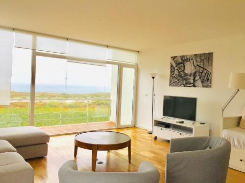 a living room with a couch and a tv at Santa Cruz Ocean View Villa in Bombardeira