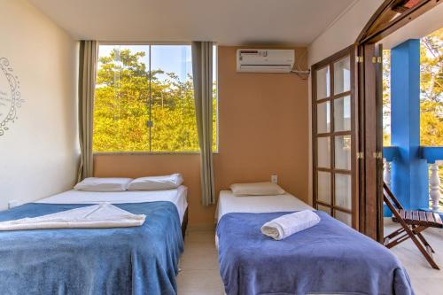 Duas camas num quarto com uma janela em Pousada Barra da Tijuca no Rio de Janeiro