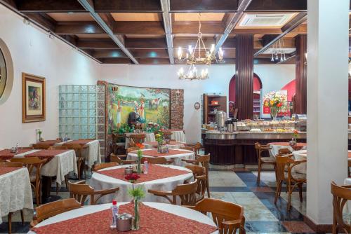 a restaurant with tables and chairs and a bar at Hotel Glória Blumenau in Blumenau