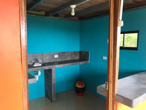 La salle de bains est pourvue d'un lavabo et d'un mur bleu. dans l'établissement Cabaña La Piña, à San Rafael