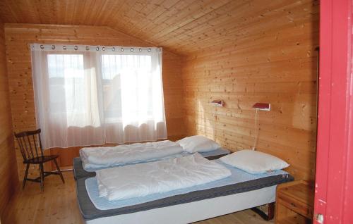two beds in a wooden room with a window at 3 Bedroom Stunning Home In Farsund in Farsund