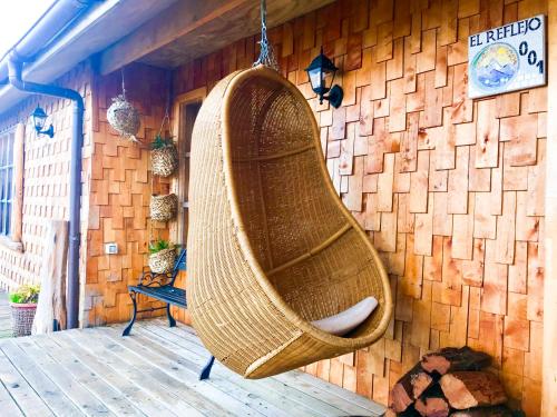 a large wicker swing hanging from a wall at El Reflejo Lodge Spa - Queilen - Chiloé in Queilén