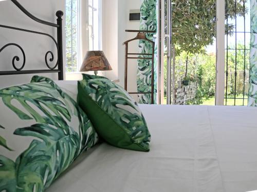 Una cama con almohadas verdes y blancas y una lámpara. en Il Giardino Del Nespolo, en Arcola