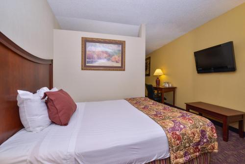 a hotel room with a bed and a flat screen tv at Lamplighter Inn-South in Springfield