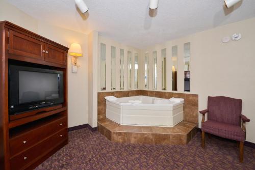 a bathroom with a tub and a tv and a chair at Lamplighter Inn-South in Springfield