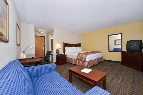 a hotel room with a bed and a couch and a tv at Lamplighter Inn-South in Springfield