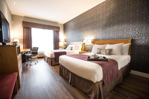 a hotel room with two beds and a television at Cambridge Hotel and Conference Centre in Cambridge