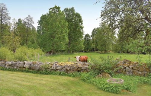 a cow standing next to a stone wall at Awesome Home In Ryd With Kitchen in Ryd