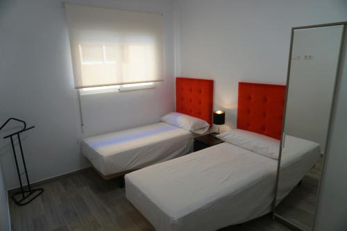 Una pequeña habitación con dos camas y un espejo. en Apartamentos Ondeanos, en La Carolina