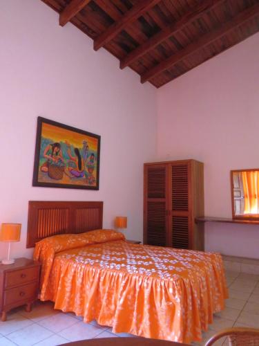 a bedroom with a bed with an orange bedspread at Posada Cumpanama in Yurimaguas