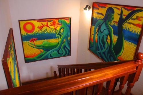 two paintings on the wall next to a wooden staircase at Posada Cumpanama in Yurimaguas