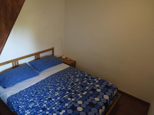a bedroom with a bed with blue and white sheets at Rifugio Alpino Salvatore Citelli in Fornazzo