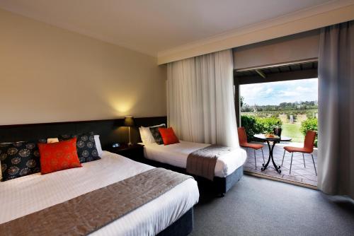 a hotel room with two beds and a balcony at Harrigan's Hunter Valley in Pokolbin