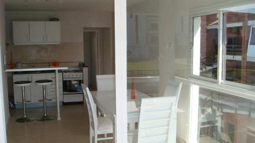una cocina con una mesa y sillas blancas y una ventana en Pinamar Alquilo Depto A 150 Mts Del Mar, en Pinamar