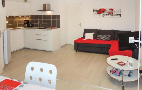 a living room with a red couch and a kitchen at Nice Apartment In Gruissan With Kitchen in Gruissan