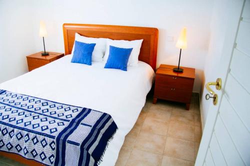a bedroom with a bed with blue pillows and two lamps at Panoramic Beach View Apartment (T2) in Caparica in Costa da Caparica