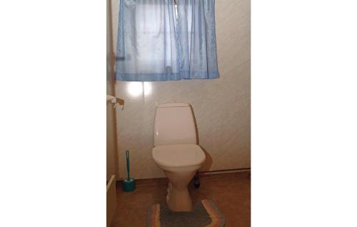a bathroom with a toilet and a blue curtain at Bjerkly in Trøan