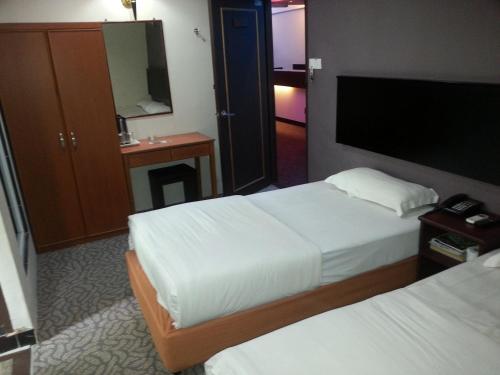 a hotel room with two beds and a flat screen tv at Oriental Inn in Kuching