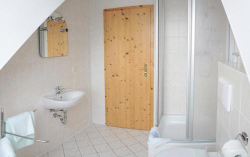 La salle de bains est pourvue d'un lavabo et d'une porte en bois. dans l'établissement Pension & Gasthaus Kahren, à Kahren