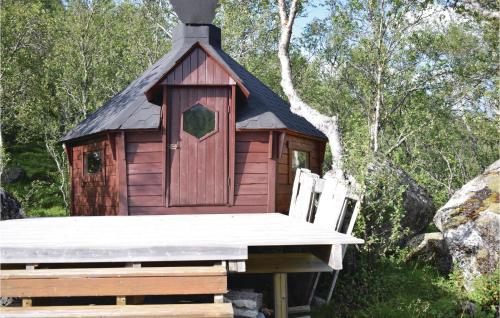 a small red house with a table and two chairs at Tjeldøya in Dragland