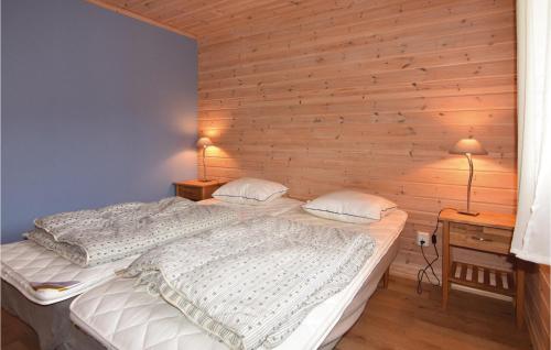 two beds in a bedroom with a wooden wall at 3 Bedroom Beautiful Home In Årjäng in Årjäng