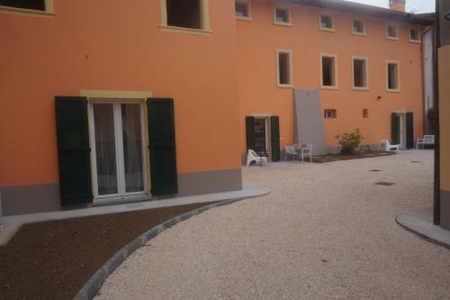 an orange building with green doors and a courtyard at La casa di Edone in Monzambano