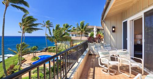 a balcony with chairs and a view of the ocean at Whalers Cove in Poipu in Koloa
