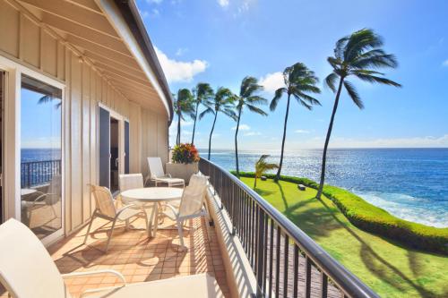 a balcony with a table and chairs and the ocean at Whalers Cove in Poipu in Koloa