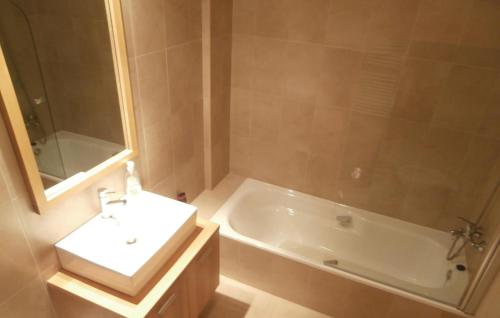 ein Badezimmer mit einem Waschbecken, einer Badewanne, einem weißen Waschbecken und einem Spiegel in der Unterkunft Nice Apartment In Sucina With 2 Bedrooms, Wifi And Outdoor Swimming Pool in Sucina