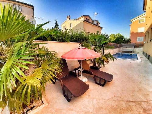 a patio with chairs and an umbrella and a pool at Villa Sara in Poreč