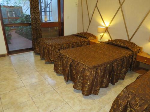 a hotel room with three beds and a window at Posada Cumpanama in Yurimaguas