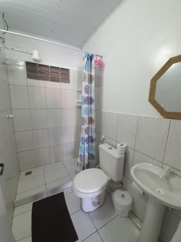 a white bathroom with a toilet and a sink at Canema Pousada in Arraial do Cabo