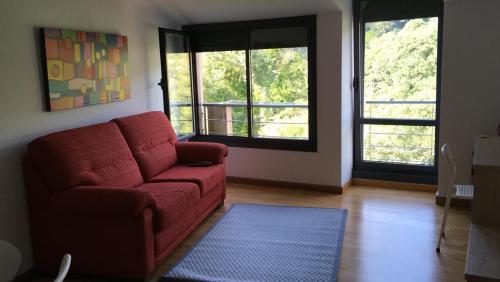 a living room with a red couch and two windows at VILLA FUENTES in Caldas de Reis