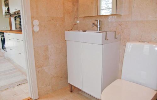 Baño blanco con lavabo y silla en Nice home in Mellerud with 1 Bedrooms and WiFi, en Mellerud