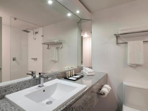 a bathroom with a sink and a toilet and a mirror at Hotel Grand Chancellor Adelaide in Adelaide