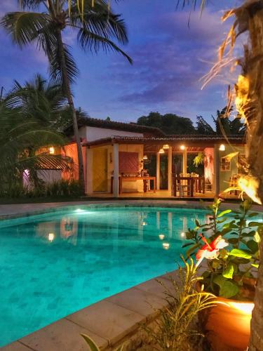 a swimming pool in front of a house at night at Pousada Ilha do Vento in São Miguel do Gostoso