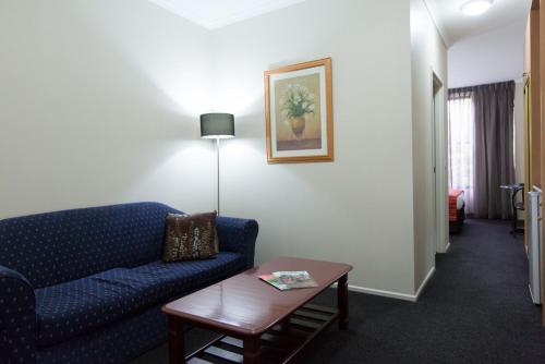 a living room with a blue couch and a table at Barkly Motorlodge in Ballarat