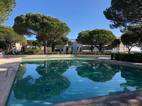 une piscine d'eau avec des arbres et une maison dans l'établissement Appartement dans résidence d'exception, à Mandelieu-la-Napoule
