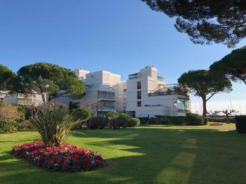 un grand bâtiment blanc avec des fleurs dans un parc dans l'établissement Appartement dans résidence d'exception, à Mandelieu-la-Napoule